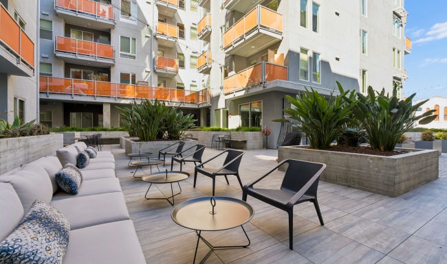Courtyard area with various outdoor seating areas and large planter boxes full of plants.
