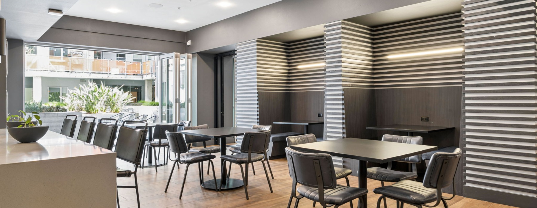 resident lounge with three square tables of four seats. Two built in banquettes and a collapsible nano door that opens up to the courtyard