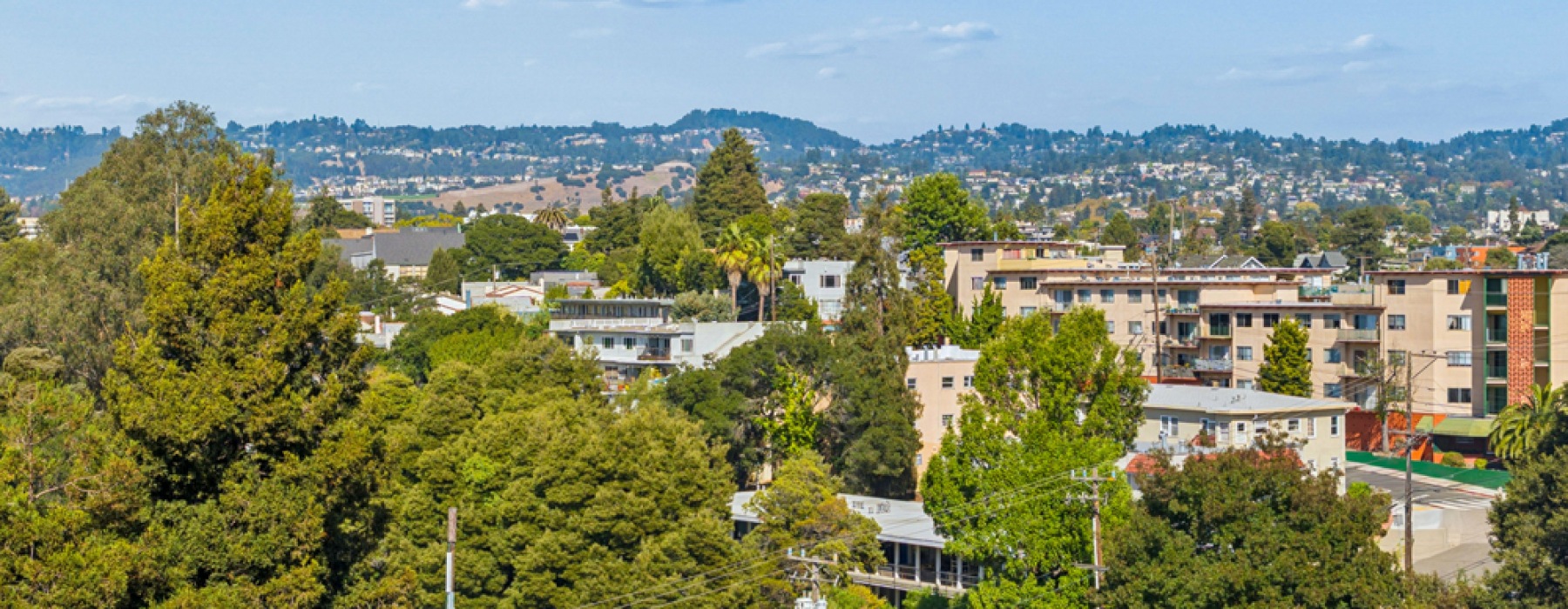 A view of a city from a high vantage point with buildings and trees in the foreground.